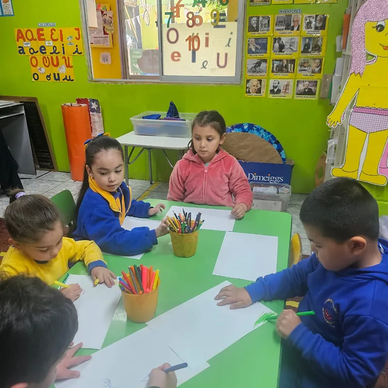 Párvulos dibujando con lápices de colores en la mesa de su sala