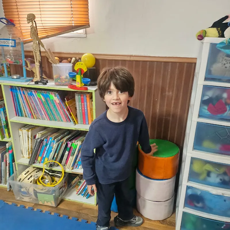 Niño junto a la biblioteca de la sala en Mi Rincón Mágico