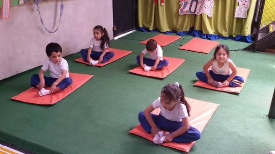 Párvulos practicando ejercicios de respiración y posturas de yoga infantil en sala