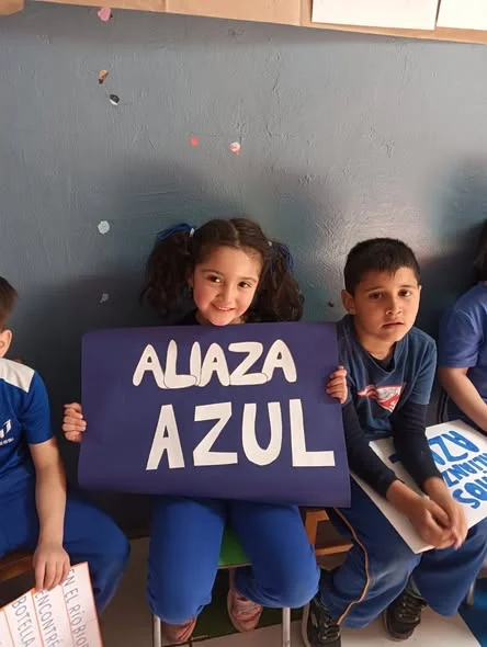 Niña y niño de Kínder sosteniendo la pancarta Alianza Azul en el aniversario del jardín