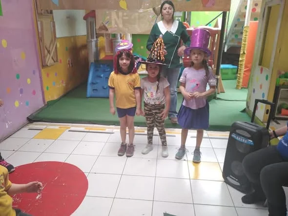 Niñas con sombreros decorados junto a su educadora en el aniversario 2019 de Mi Rincón Mágico