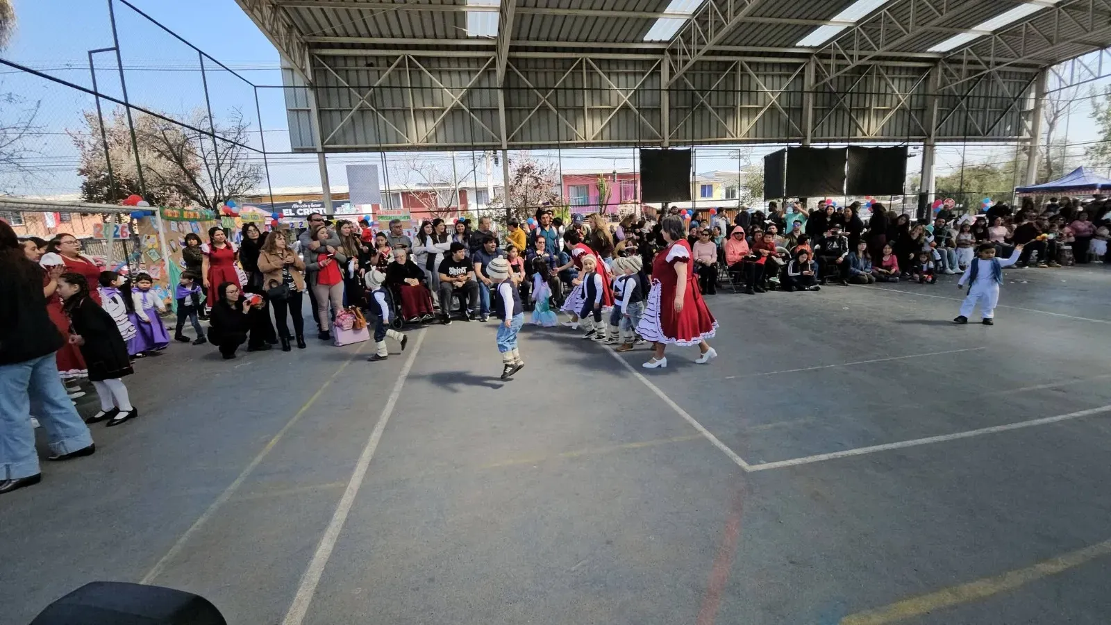 Párvulos con gorros de lana en la presentación de danza chilena junto a su educadora