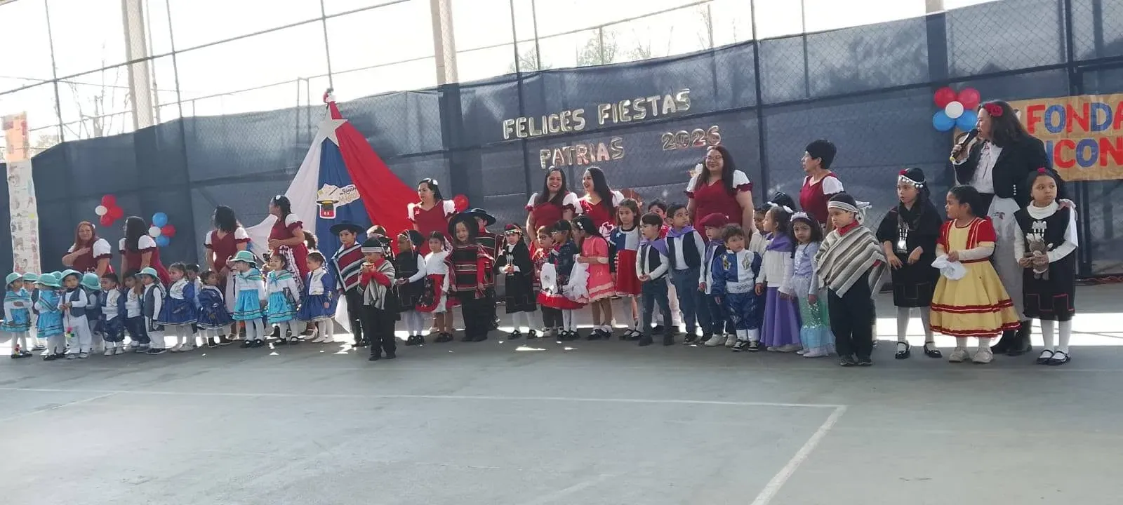 Presentación grupal de todos los párvulos con trajes típicos y equipo de educadoras
